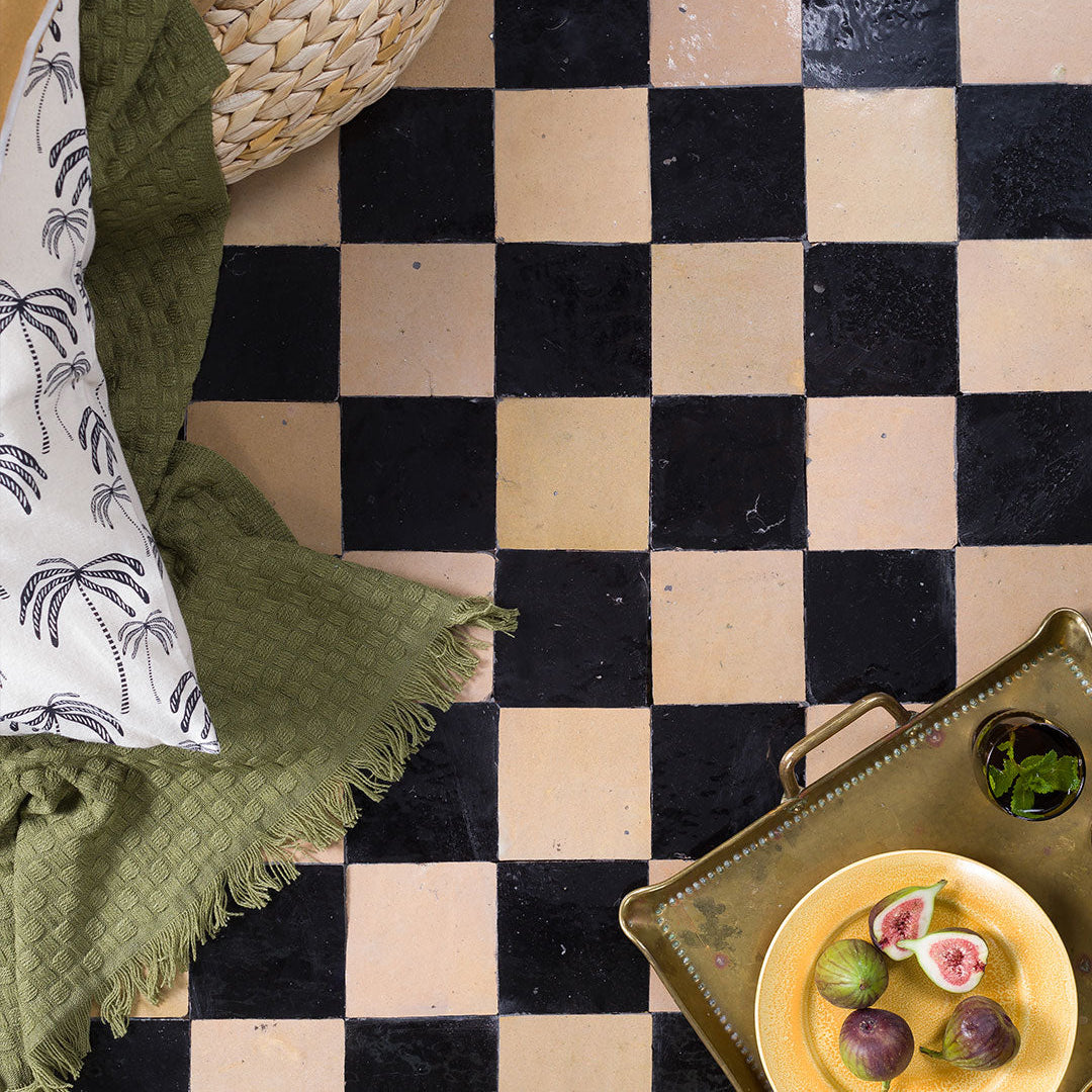 Checkered floor with green blanket and decorative tray with figs