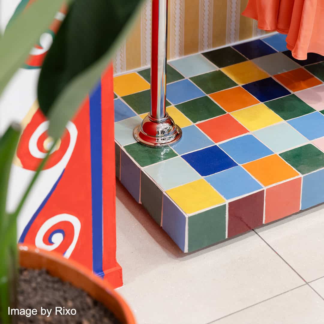 Colorful tiled floor with bright squares in red, blue, yellow, and green, with a plant pot in the foreground.