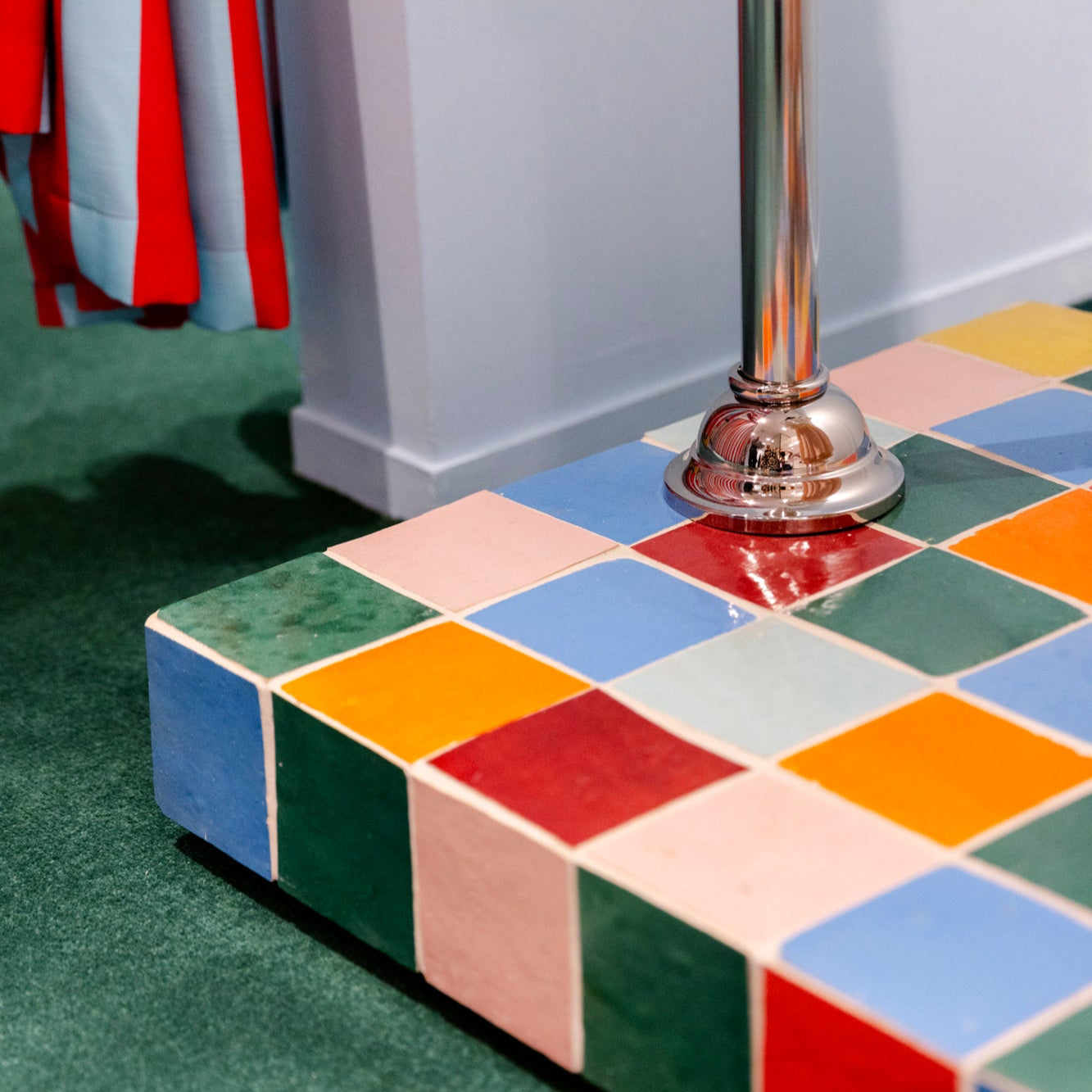 Colorful tiled step with a metallic pole and striped fabric in the background