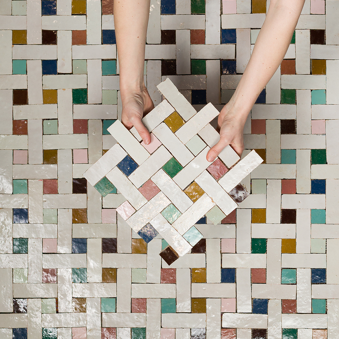 Colorful woven-pattern tile floor made of white rectangular tiles interlaced with small squares in shades of teal, pink, yellow, brown, and green. 