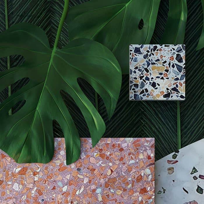Neutral terrazzo tile surface with multicolored stone chips in beige, black, gray, and warm earthy tones.