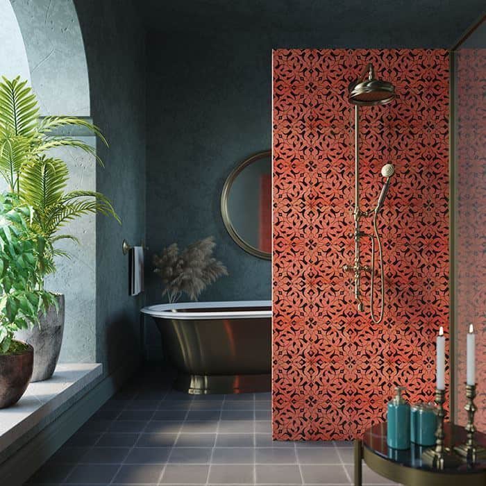 Modern bathroom with a freestanding tub, lush plants, and a patterned red tile shower wall with brass fixtures.