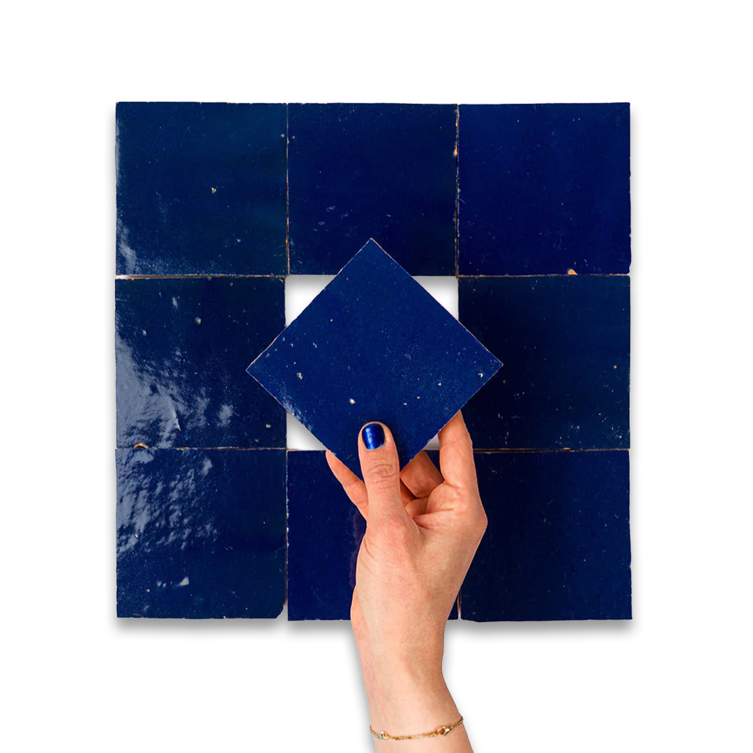 Hand holding a blue tile against a larger grid of blue tiles on a white background