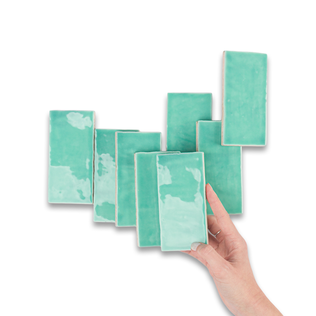 Set of teal ceramic tiles with a hand holding one tile against a white background