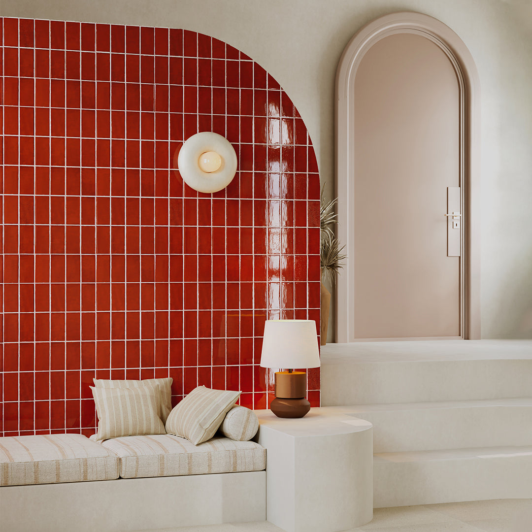 Modern interior with a red tiled wall, white bench, and lamp.