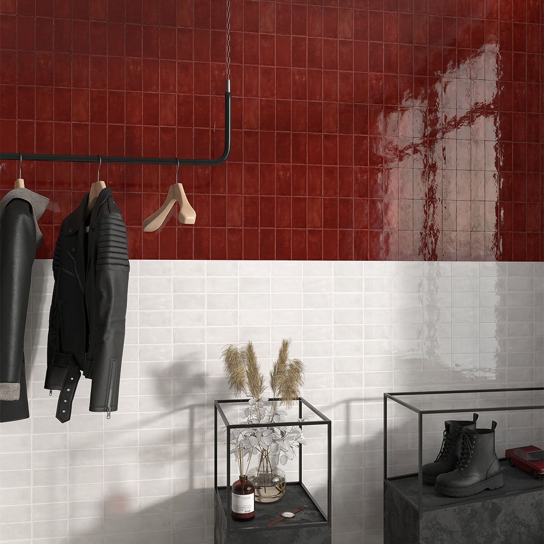 Modern interior with red and white tiled walls, black leather jackets, and a glass table with decorative items.