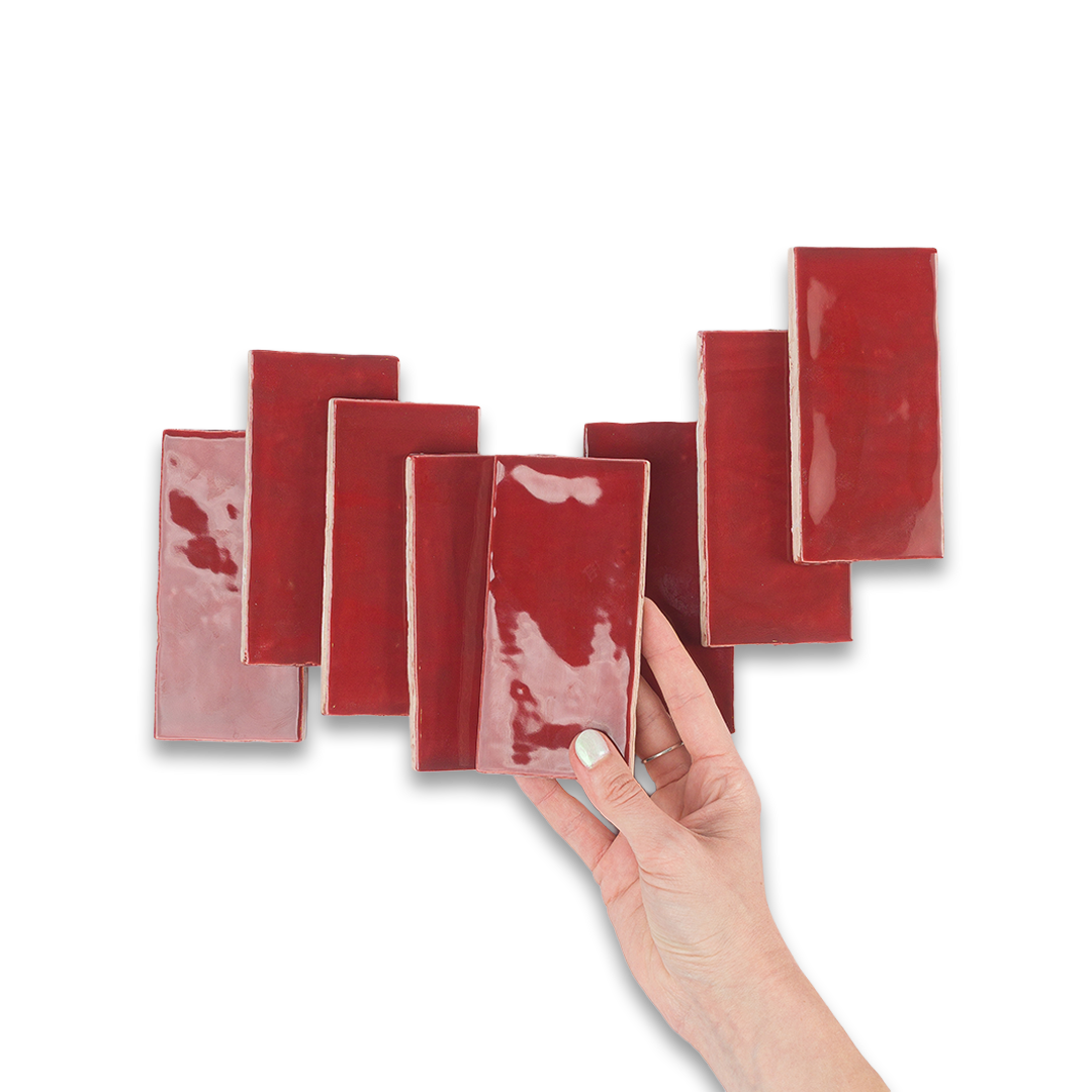 Hand holding a red ceramic tile against a white background