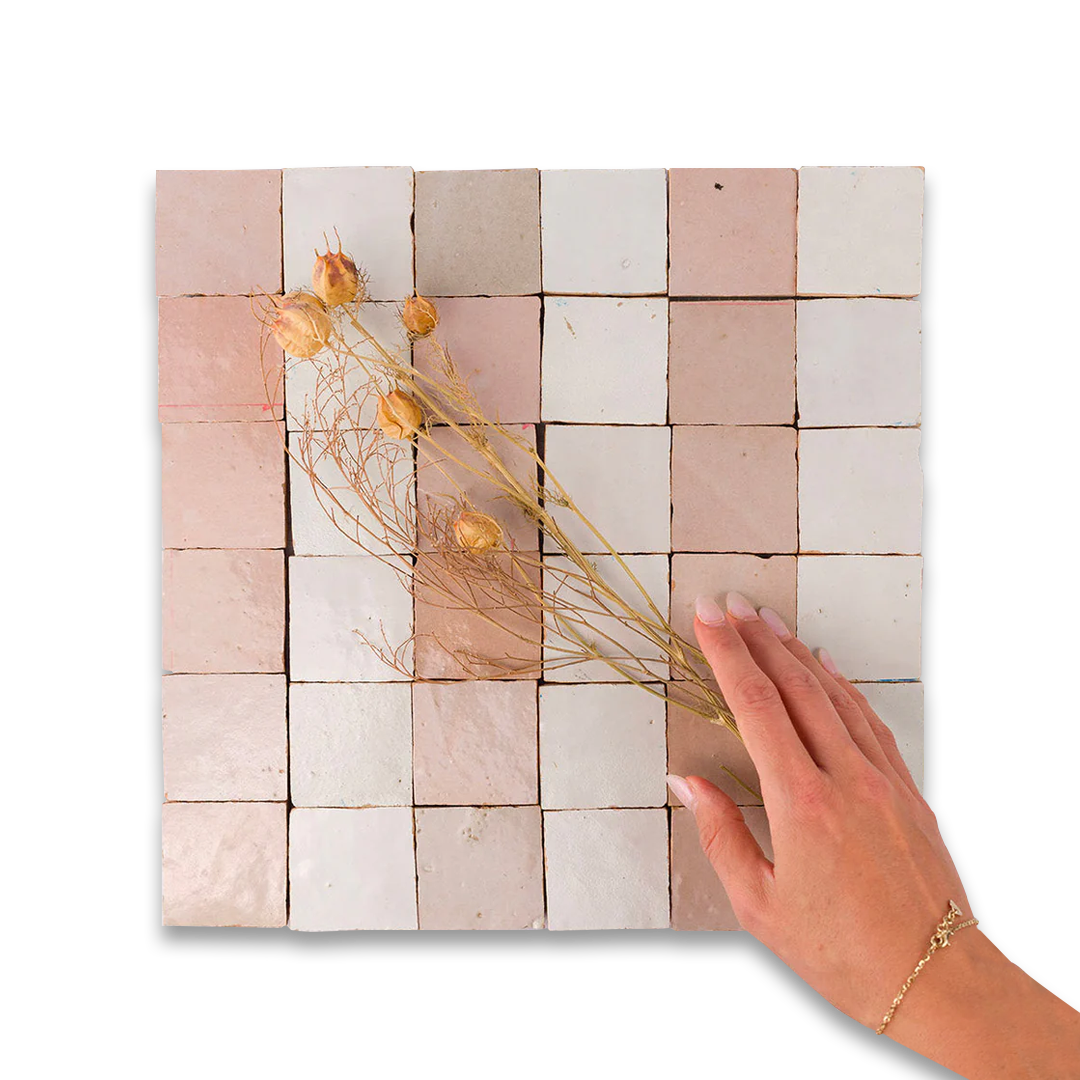 Handmade tile wall art with dried flowers and a hand for scale on a white background