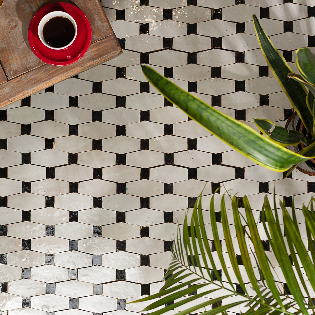 Hexagonal tile pattern with a cup of coffee and plant leaves on a wooden surface.