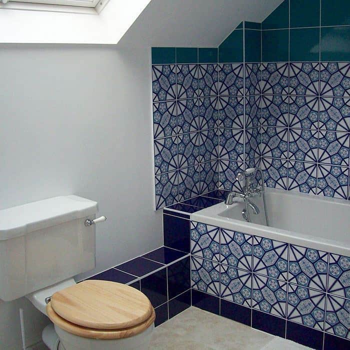 Bathroom with blue patterned wall tiles, white bathtub, and geometric mosaic tile design.