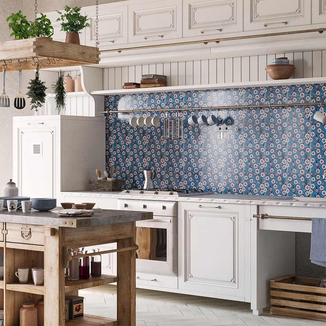 Rustic kitchen with blue patterned tile backsplash, white cabinetry, wooden island, hanging utensils, and farmhouse-style decor accents.