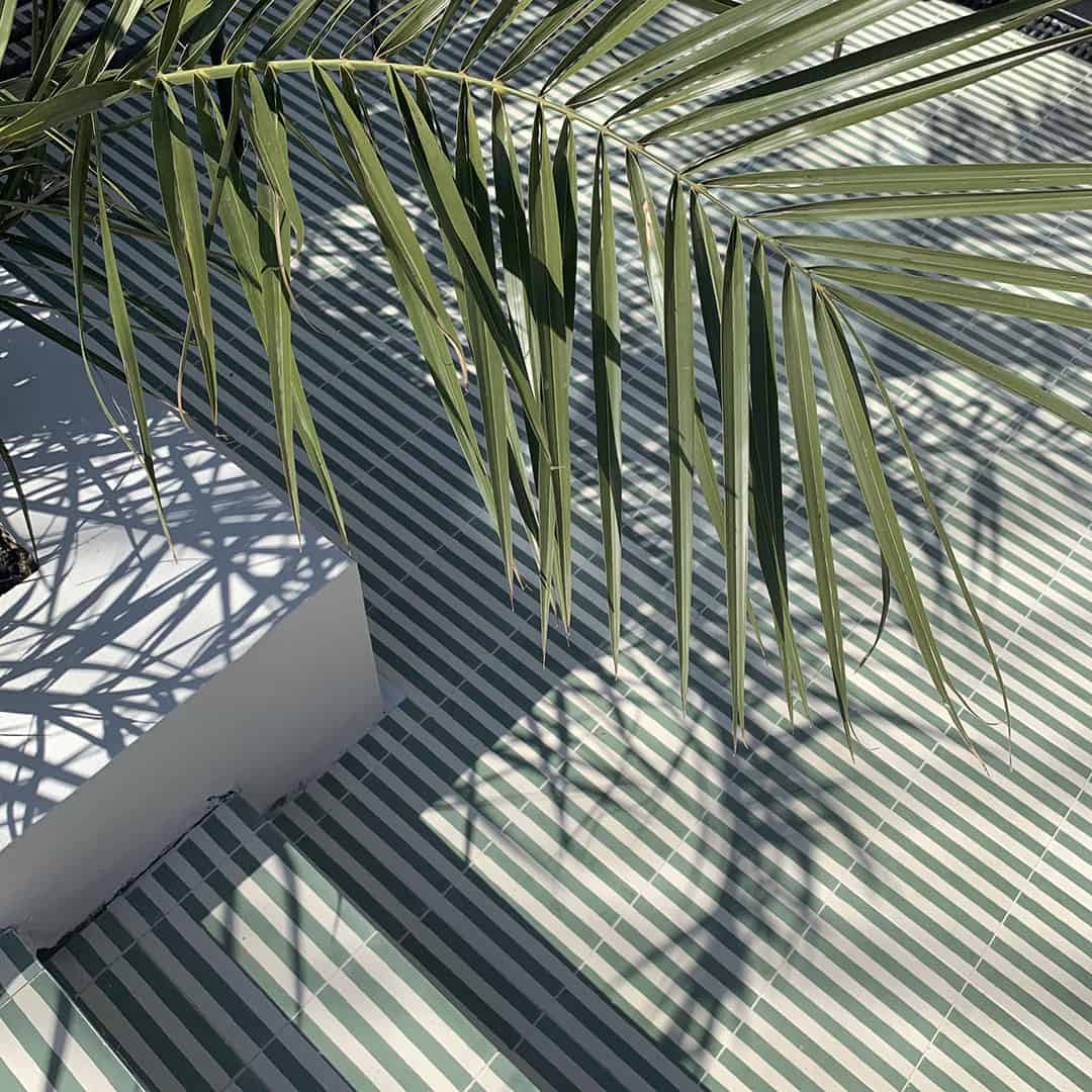 Square cement tile with alternating vertical green and white stripes, creating a clean, minimalist pattern.