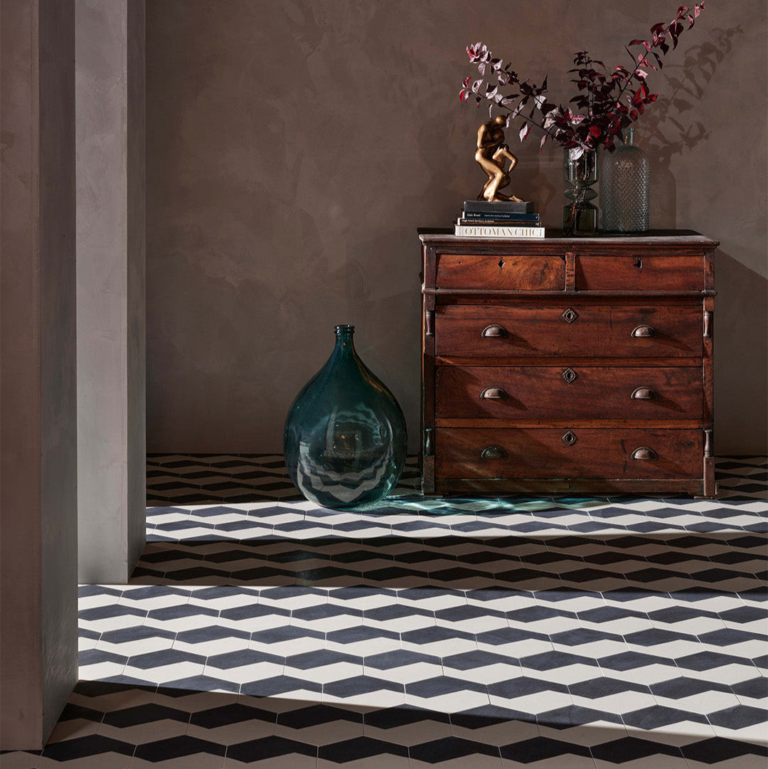 Wooden dresser with decorative items against a brown wall with a geometric black and white floor.