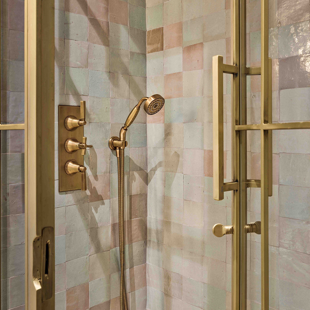 Gold shower fixture set against a tiled shower wall