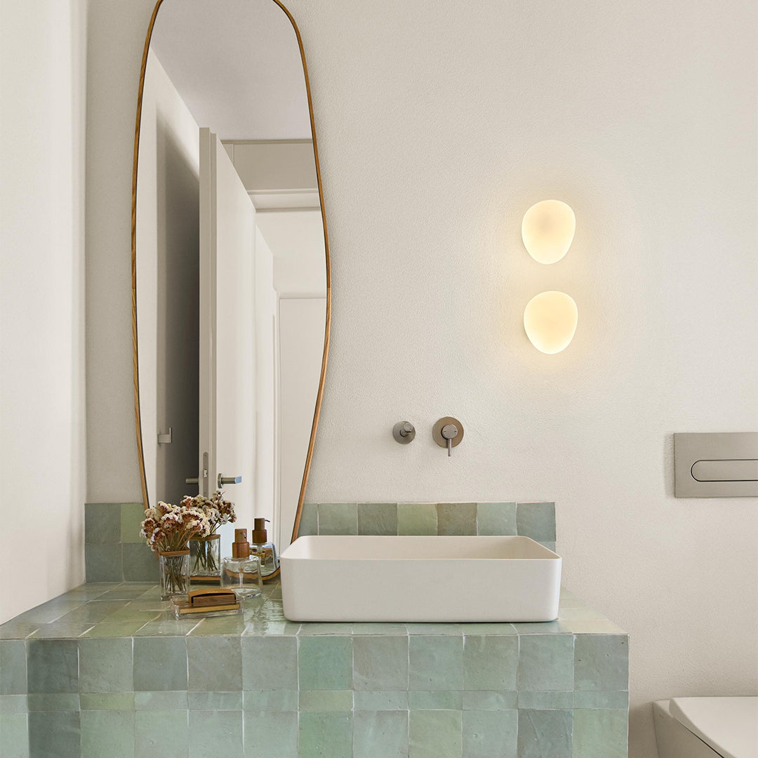 Bathroom with a rectangular sink on a tiled countertop, large mirror, and wall lights.