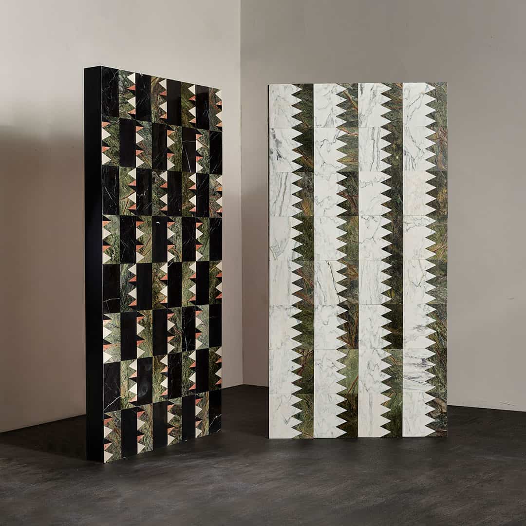 Two large marble tile panels with geometric patterns in black, green, and white, displayed in a modern interior setting.