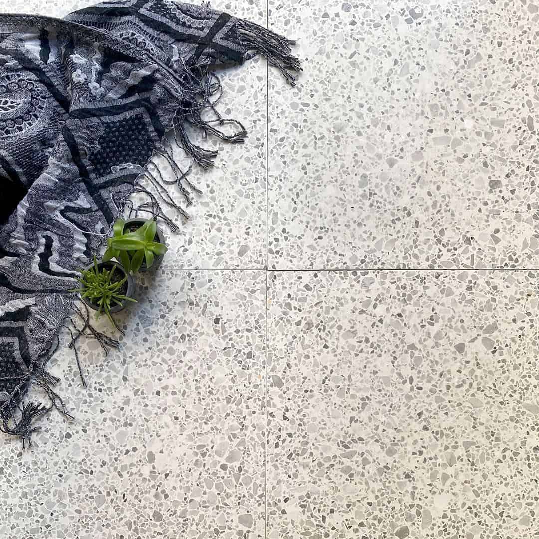 Light gray terrazzo tile surface with fine, evenly distributed stone chips in soft neutral tones.