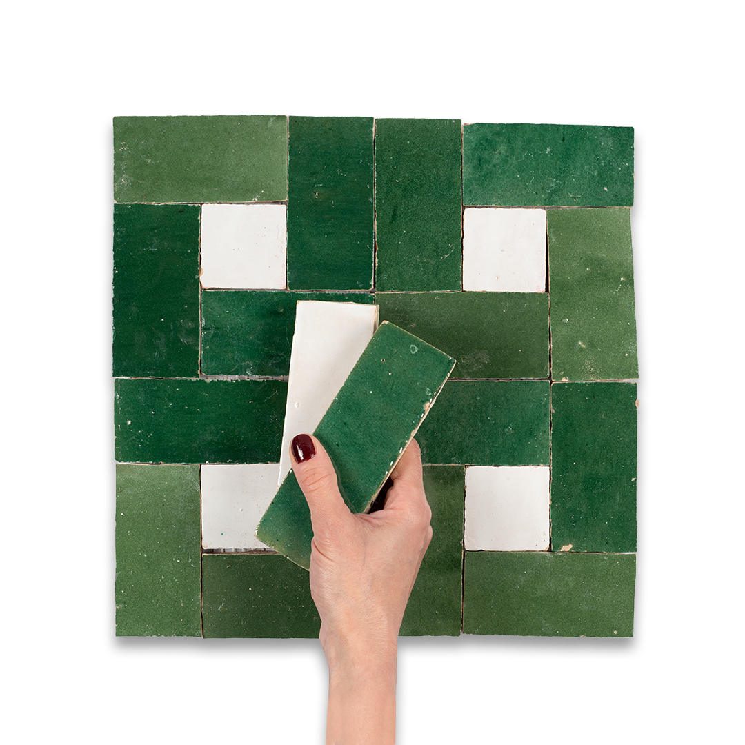 Hand holding a green tile against a mosaic of green and white tiles on a white background