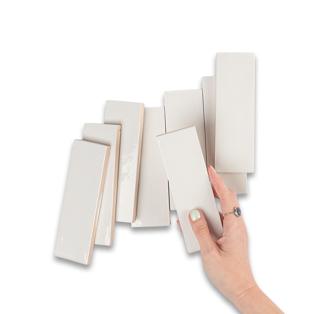Hand holding a set of white ceramic tiles against a white background