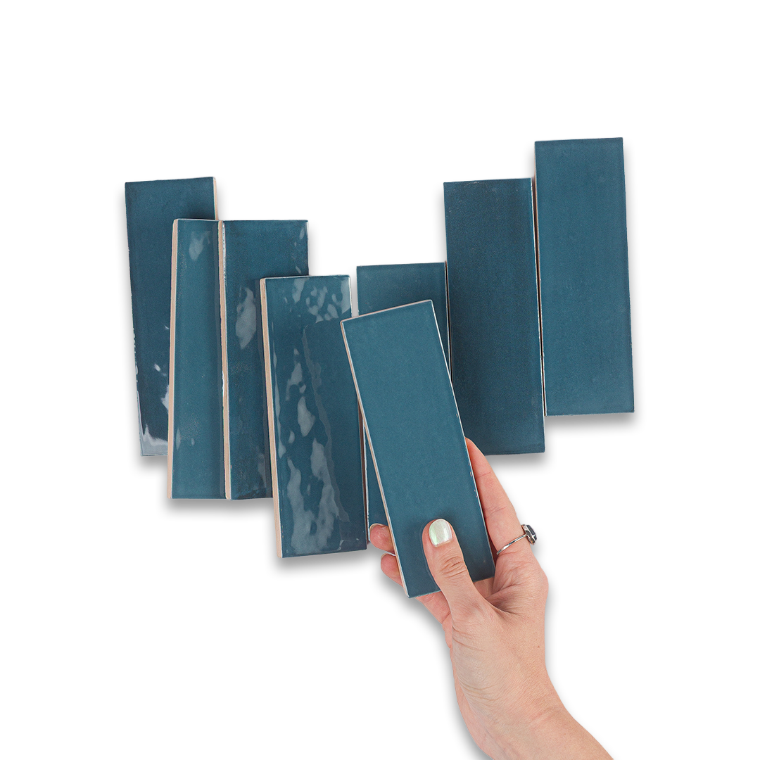 Hand holding a blue tile sample with other tiles in the background on a white background
