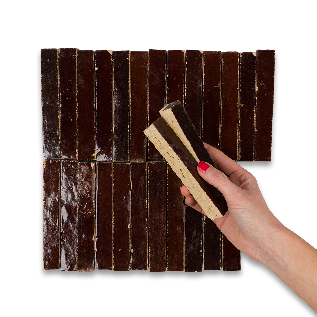 Hand holding a piece of chocolate against a background of chocolate bars
