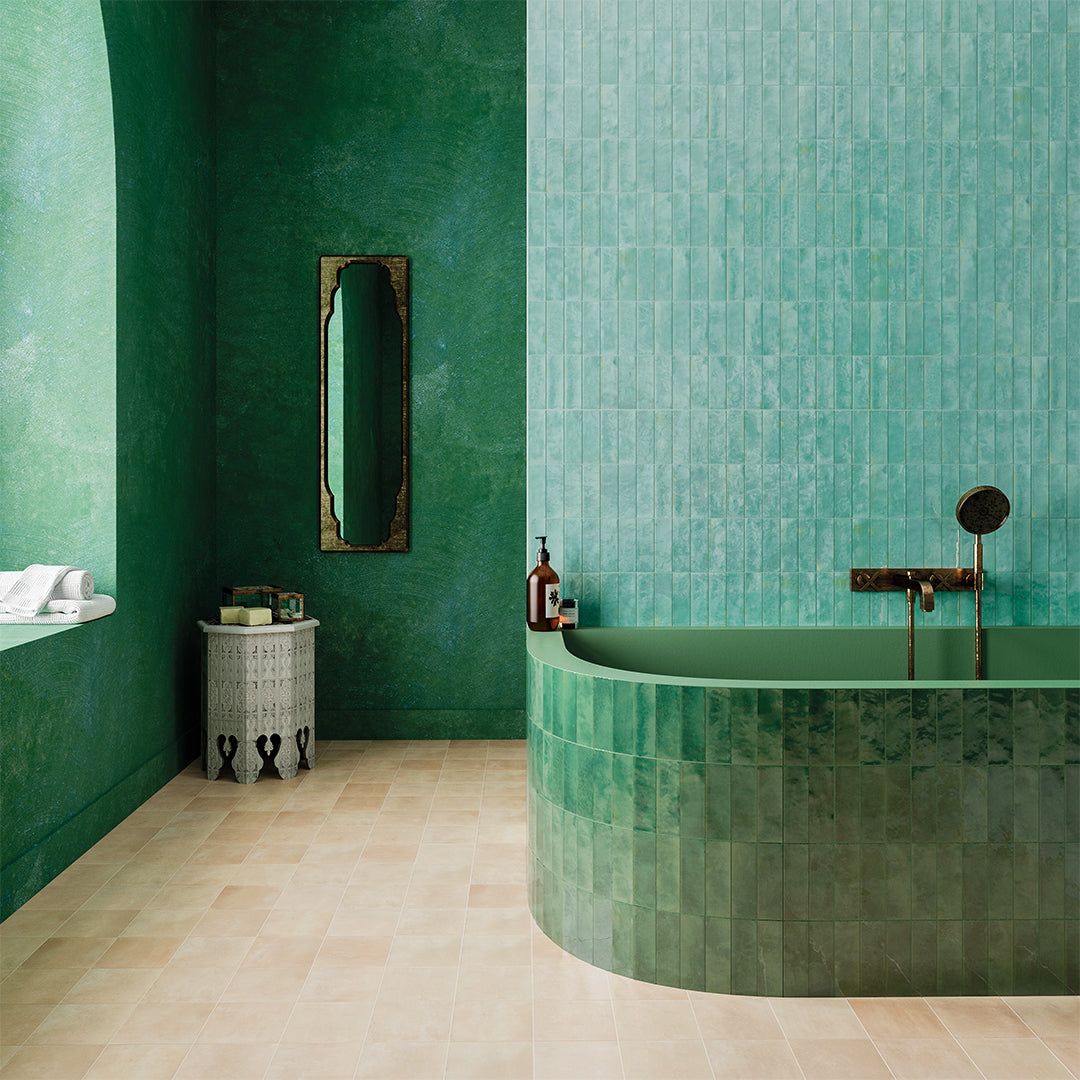 Modern bathroom with green tiles and a curved bathtub.