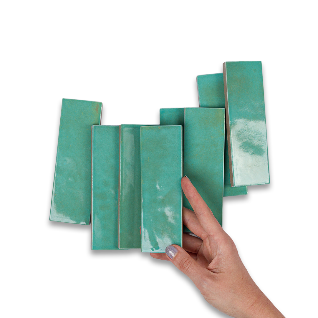 Hand holding a set of teal ceramic tiles against a white background