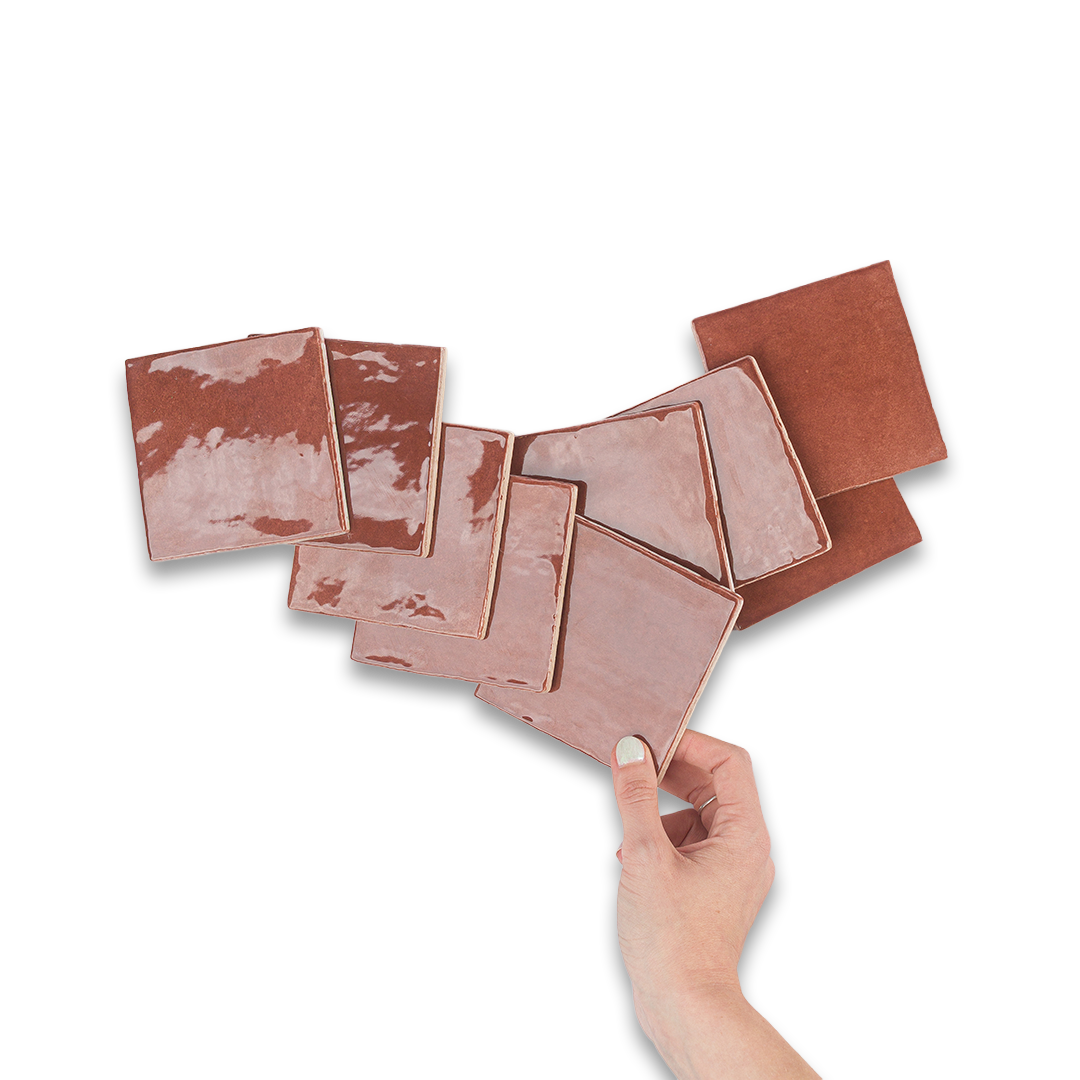 Hand holding a set of rose gold square coasters on a white background