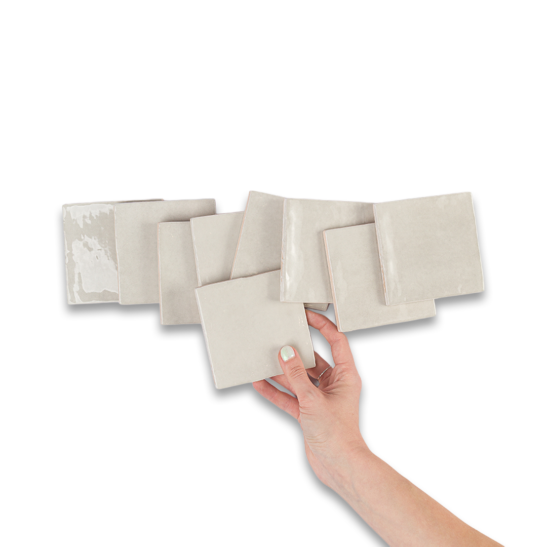 Set of beige square tiles with a hand holding one tile on a white background