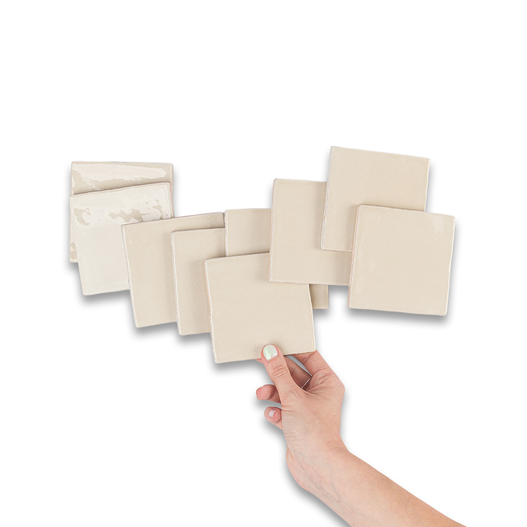 Hand holding beige square tiles against a white background