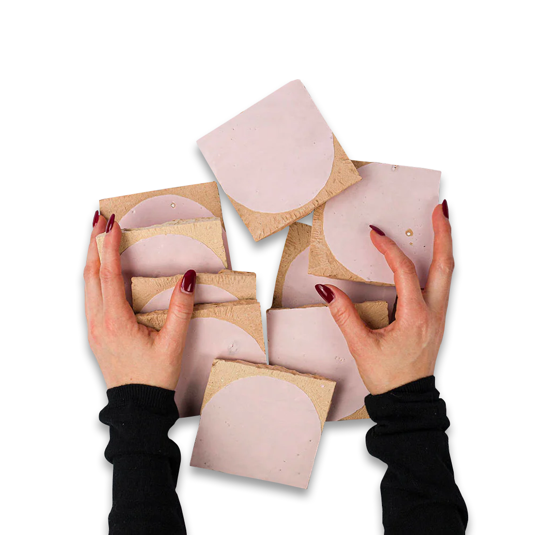 Hands holding pink silicone bra cups with cardboard backings on a white background