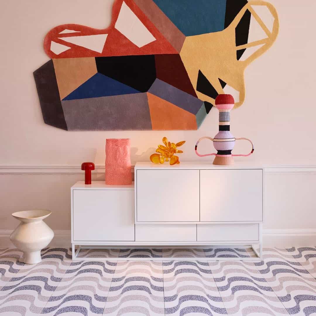 A square cement tile featuring a white background with curved, wave-like gray terrazzo patterns containing white speckles, creating a modern, rhythmic, and textured geometric design.