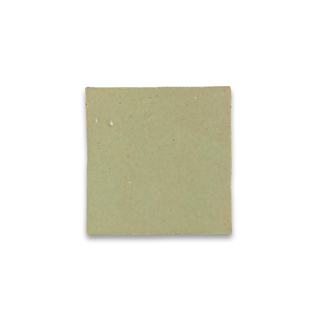 Single square ceramic tile in a muted sage green color with slightly uneven edges and a matte finish, set against a transparent checkered background.