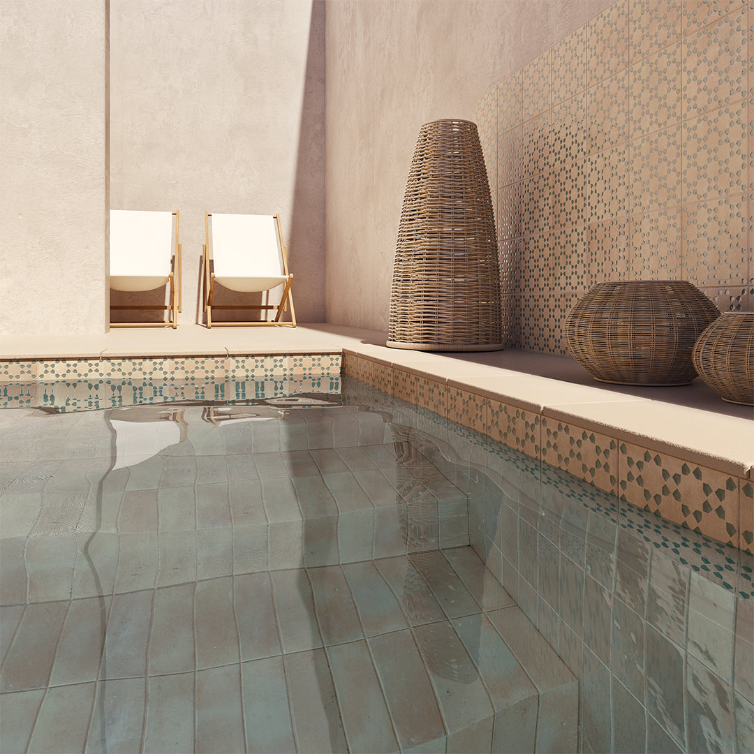 Modern indoor pool area with tiled floor, wicker chairs, and decorative elements.
