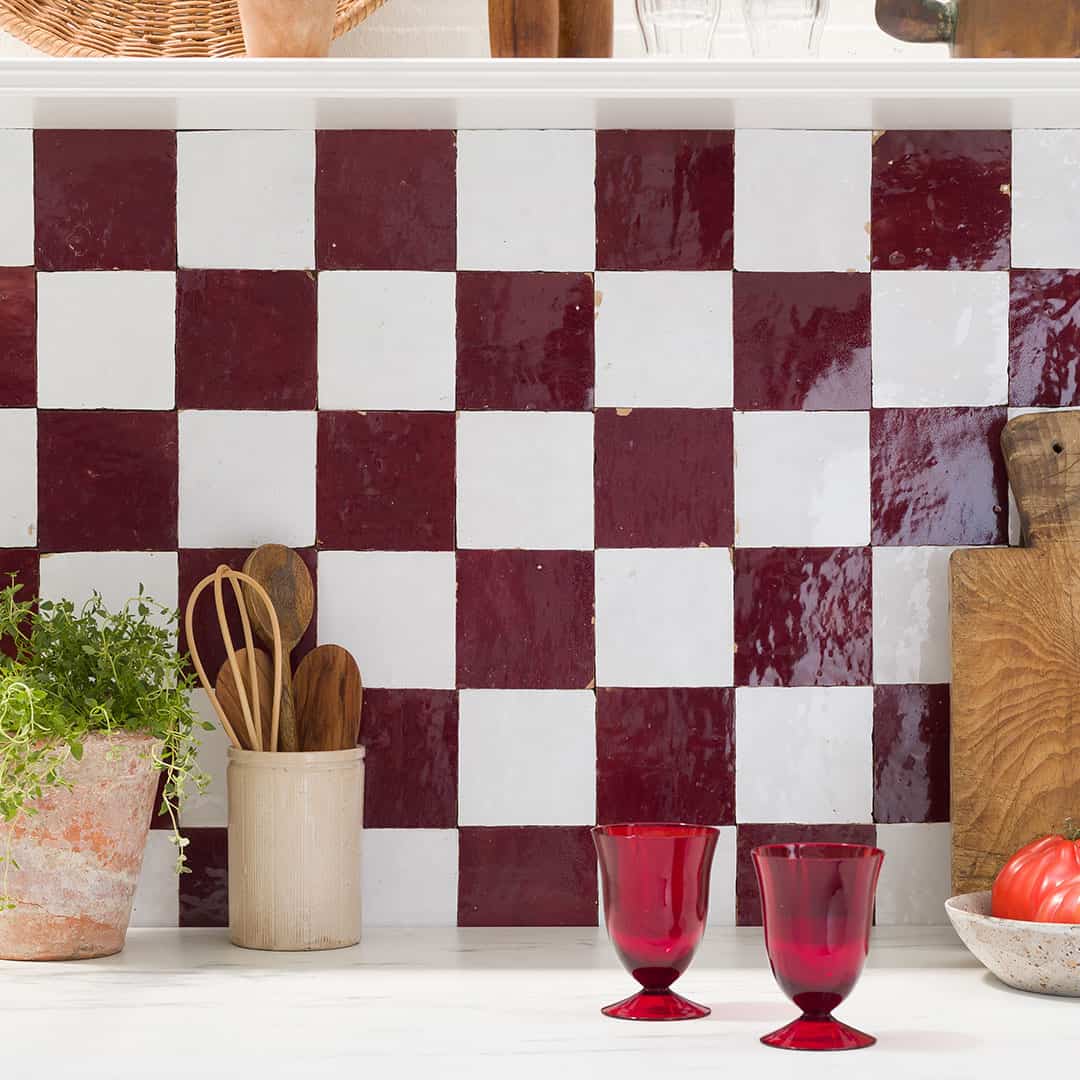 A kitchen countertop with a red and white checkerboard tile backsplash.