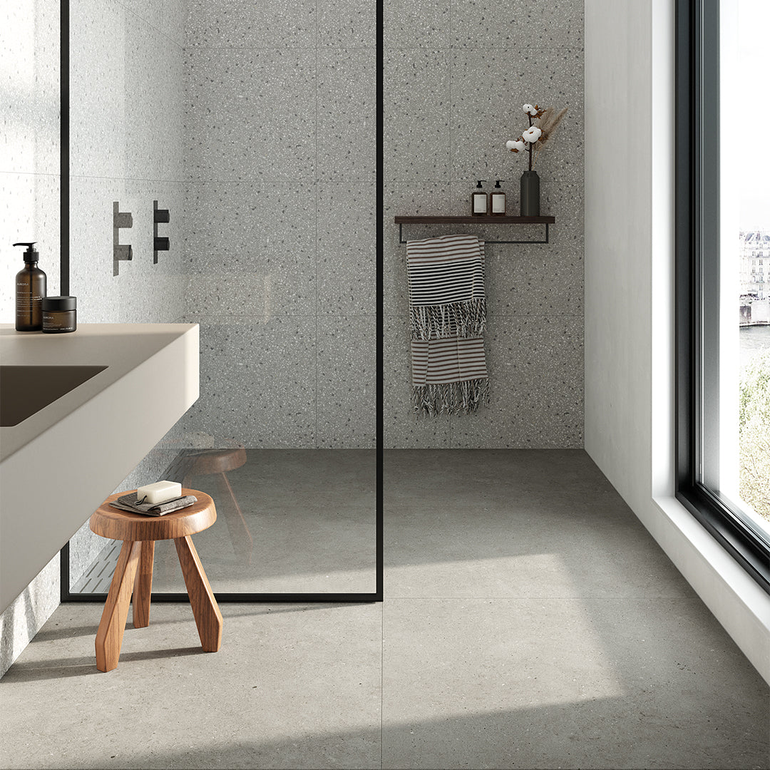 Modern bathroom with concrete walls, a wooden stool, and a mirror.