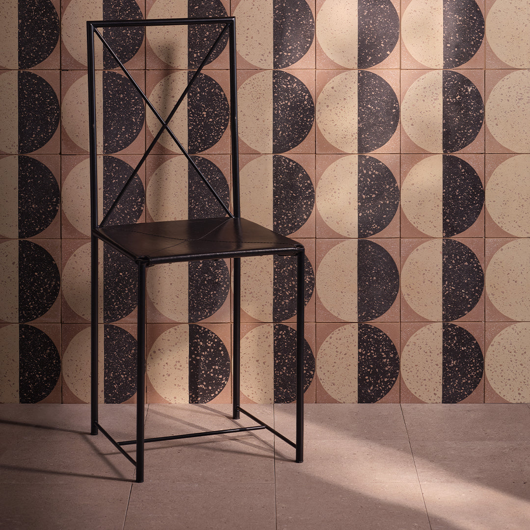 Black metal chair against a patterned tiled wall