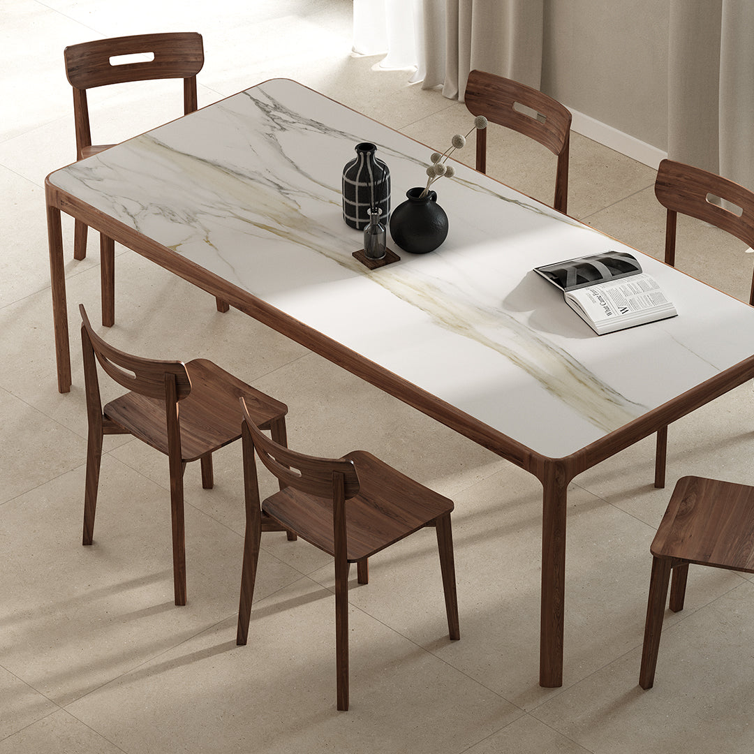 Dining table with marble-like surface and wooden chairs in a room.