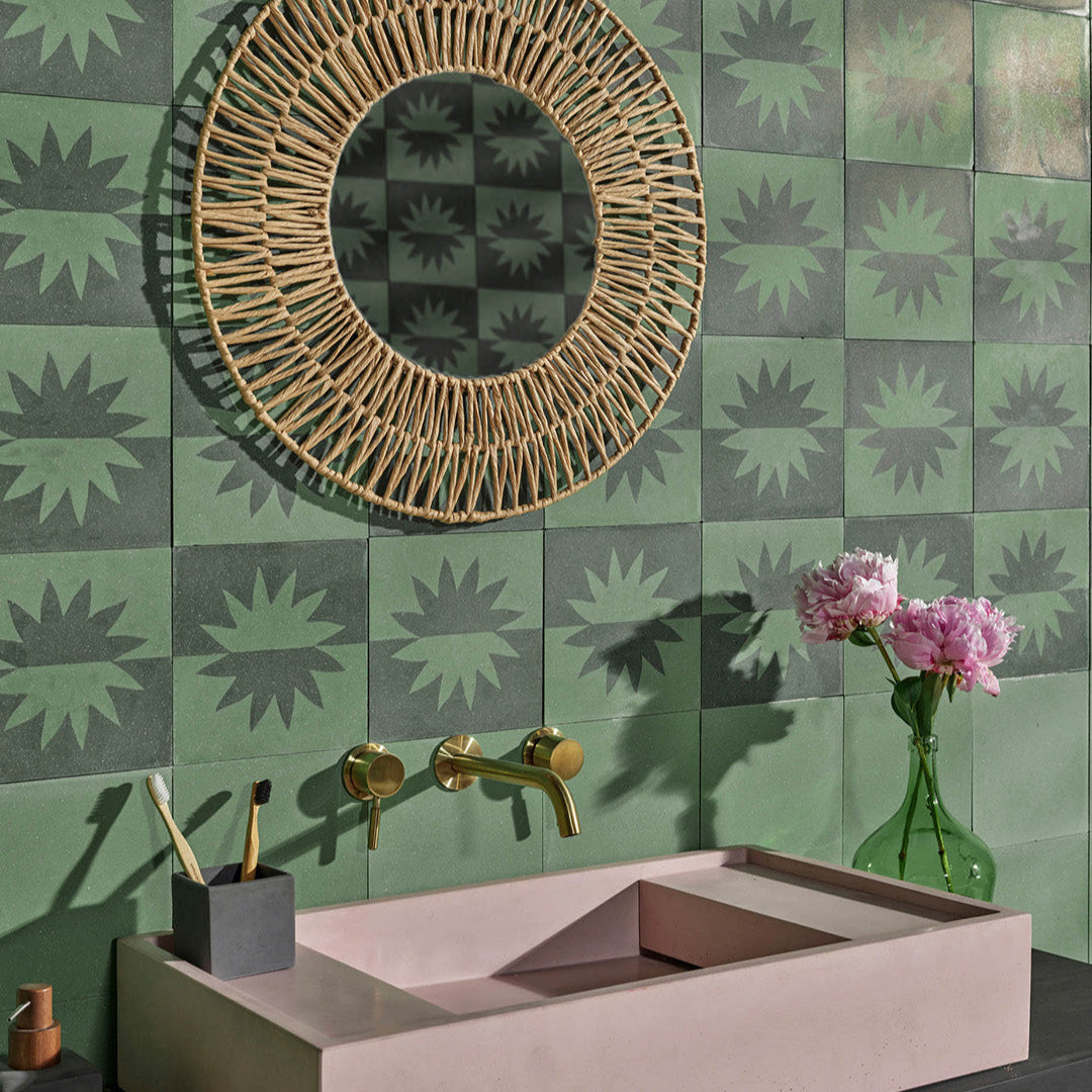 Square cement tile with symmetrical flower-like motif, mirrored across horizontal division in muted greenish-blue and beige, creating a modern minimalist design. 