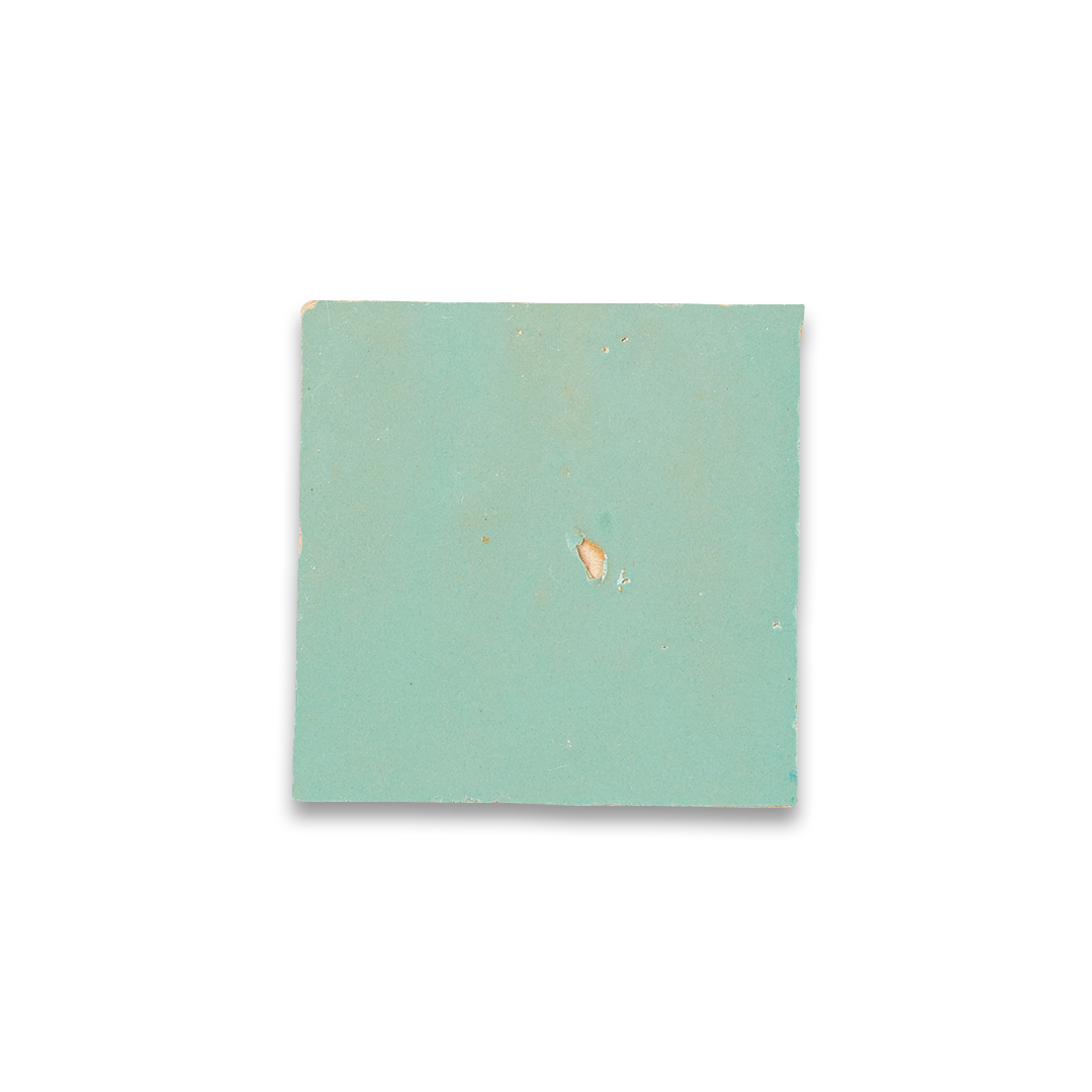 Square piece of light green paper with a small brown spot on a white background