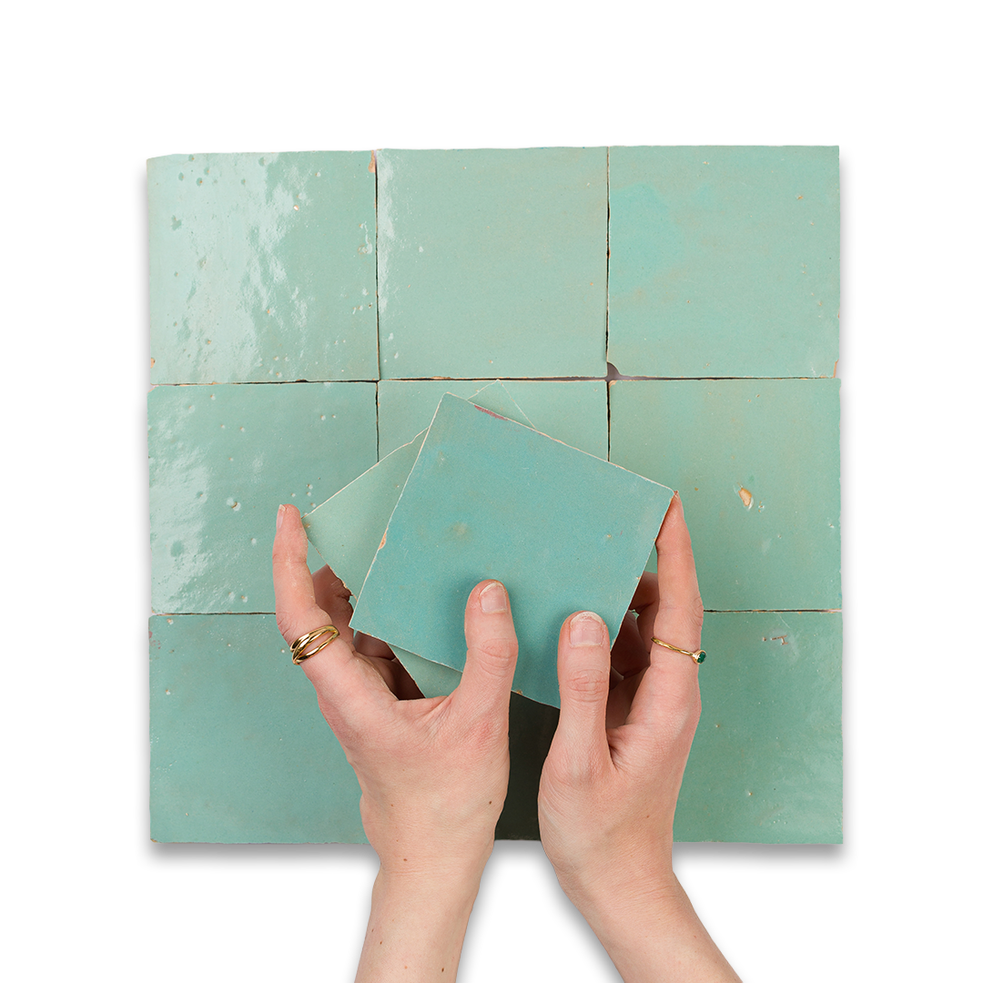 Person holding a green tile against a grid of similar tiles on a white background