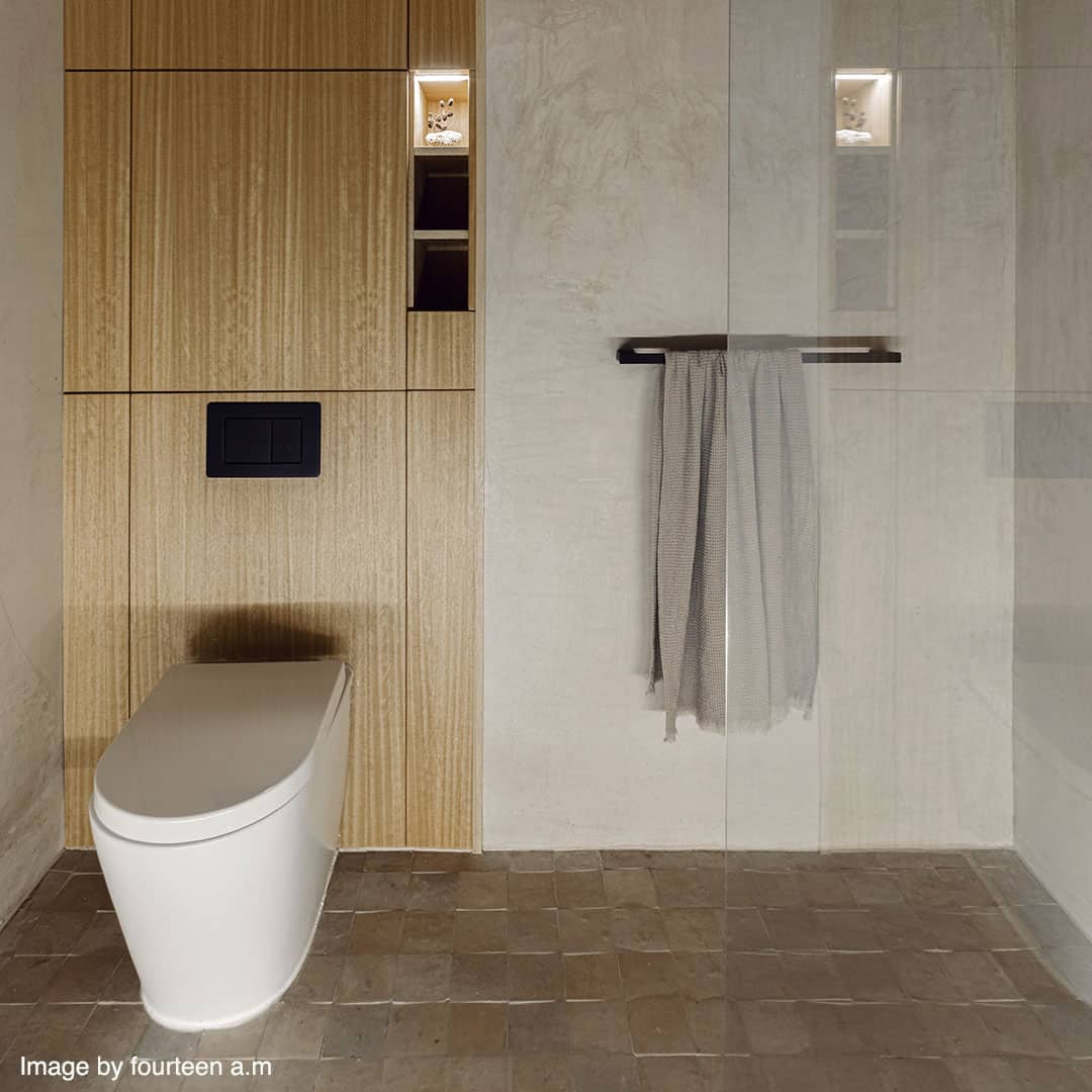 A modern bathroom with a sleek white toilet built into a wooden panel wall. 
