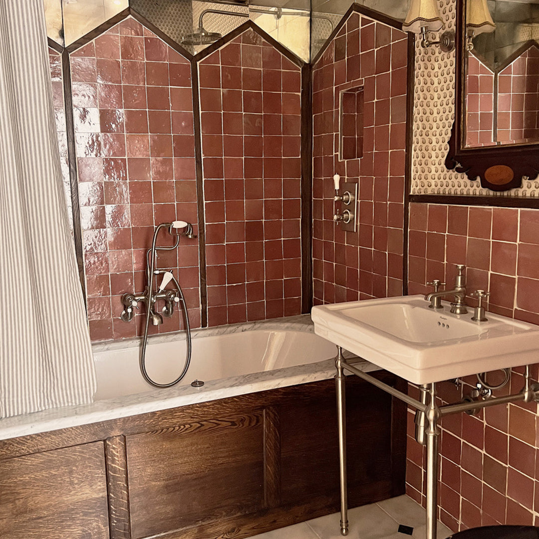 Bathroom with red tiled walls, a bathtub, and a sink.