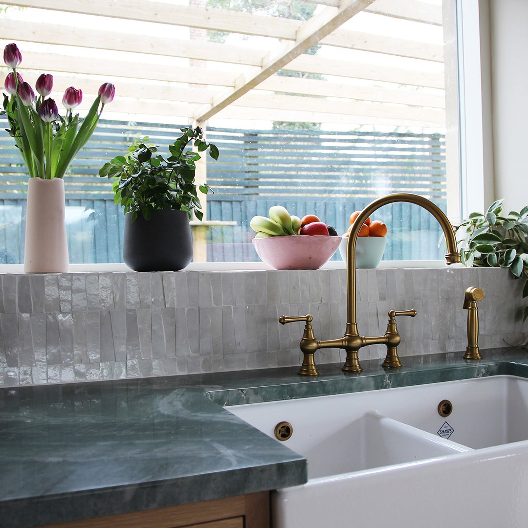 Kitchen sink area with marble countertop, brass faucet, and decorative elements.