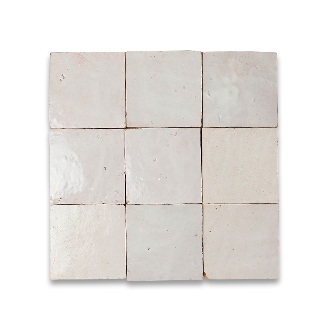 A 3×3 grid of square ceramic tiles with a glossy, light beige finish. Each tile has a slightly uneven, handmade texture with small pits and subtle color variations, set against a black background.